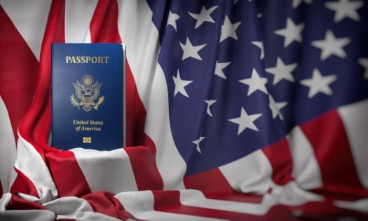 Pasaporte frente a una bandera de USA que indica la aprobación de una visa de inversionista en USA
